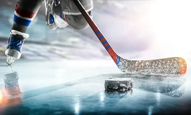 Close up of ice hockey stick on ice rink in position to hit hockey puck